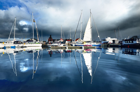 Elegant and modern sailboats (for rent) moored to a pier in a yacht marina on a cloudy day. Norway....