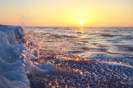 Frozen Baltic sea shore at sunset, snow texture close-up. Pink sky, golden sunlight. Picturesque...