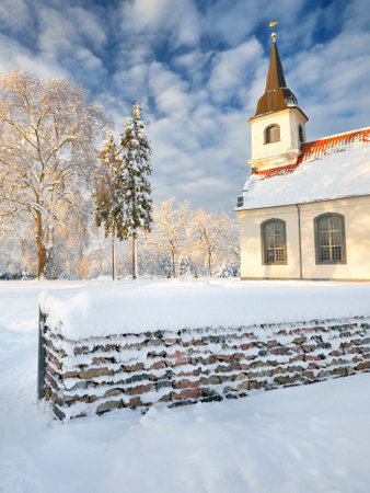 Snow-covered lutheran Baltezera Church under a cloudy blue sky, close-up. Winter rural scene. Latvia. Religion, culture, national landmark themeの写真素材