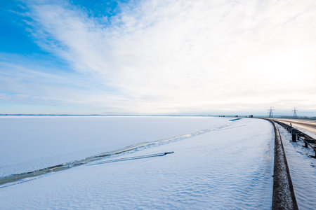 A clean highway through the snow-covered country fields after a blizzard. Dramatic cloudscape....