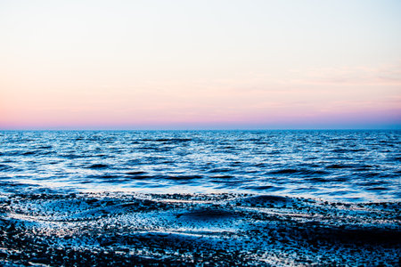 Colorful sunset. Snow-covered seacoast on a sunny winter day. Cold waves over the Baltic sea, Latvia