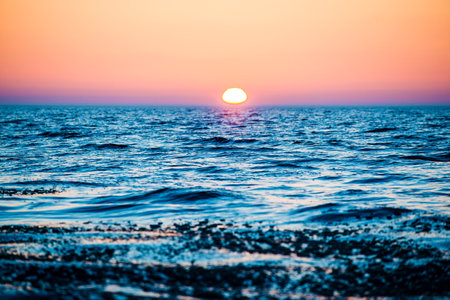 Colorful sunset. Snow-covered seacoast on a sunny winter day. Cold waves over the Baltic sea, Latviaの写真素材