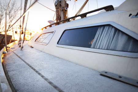 Snow-covered white yacht's deck close-up. Winter sunset. Riga, Latvia