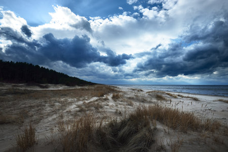 Storm clouds above the sandy shore of the Baltic sea in spring, Dramatic sky, waves and water...
