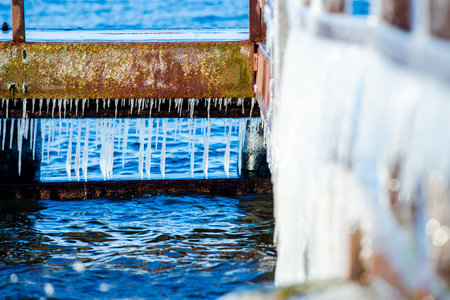Snow-covered old rusty pier on a clear sunny day. Ice fragments close-up. Baltic Sea, Latvia