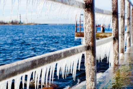 Snow-covered old rusty pier on a clear sunny day. Ice fragments close-up. Baltic Sea, Latviaの写真素材