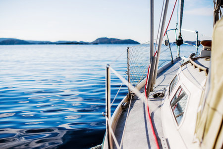 White yacht sailing on a clear sunny day. A view from the deck to the bow, mast and sails. Norway