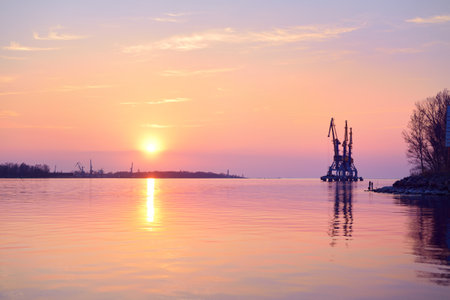 Daugava river at sunset. Port cranes in the background. Colorful cloudscape. Spring landscape. Riga, Latviaの写真素材