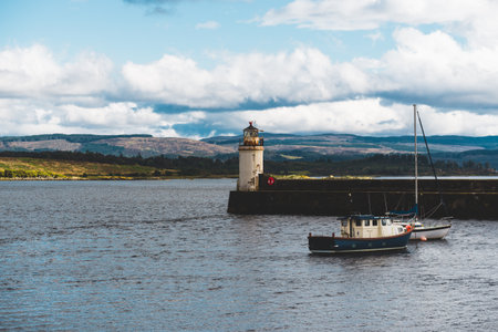 Blue fishing boat and a yacht sailing on a cloudy day, close-up. Rocky shores in the background. Dramatic cloudscape. Ardrishaig, Crinan canal, Scotland, UK. Travel destinations, cruiseの写真素材
