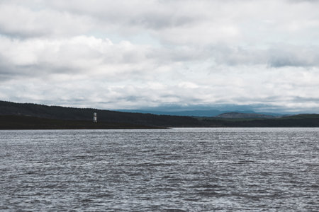 Panoramic view of the rocky shores of Tarbert under dramatic sky. Lighthouse in the background,...