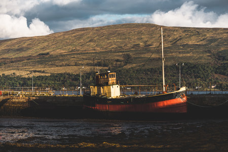 An old red fishing boat anchored near the shore of Loch Fyne, close-up. Inveraray, Argyll and Bute, Scotland, UK. Traditional craft, cruise, travel destinations, national landmarks conceptsの写真素材