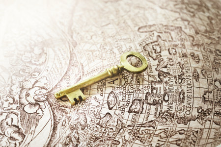 Retro styled golden antique key and old white nautical chart close-up. Vintage still life. Travel, navigation concepts, collecting, souvenir, gift, home, accessories, graphic resourceの写真素材
