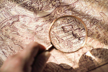 Retro copper colored magnifying glass and old white nautical chart close-up. Vintage still life. Sailing accessories. Travel, navigation concepts, collecting, graphic resource, hand lens, opticsの写真素材