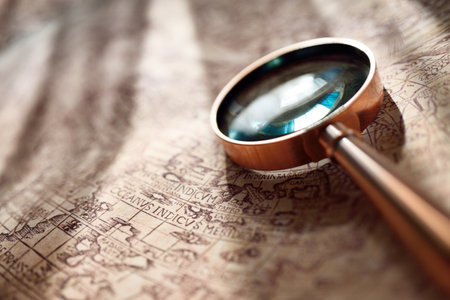 Retro copper colored magnifying glass and old white nautical chart close-up. Vintage still life....