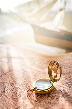 Retro styled golden antique compass (sundial), wooden tall ship scale model and old white nautical...