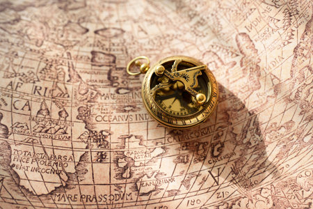 Retro styled golden antique compass (sundial) and old white nautical chart close-up. Vintage still life. Sailing accessories. Travel, navigation concepts, collecting, souvenir, gift, graphic resourceの写真素材