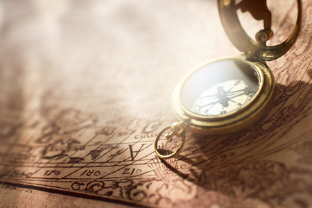Retro styled golden antique compass (sundial) and old white nautical chart close-up. Vintage still...