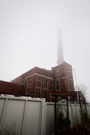An old red brick building with a pipe. Factory in a fog. Concept urban scene, landscape. Economy,...