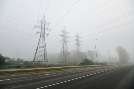 Silhouettes of the electricity power line in a thick fog, close-up. Concept urban scene, landscape. Energy, power generation, special equipment, industry, environmental damage, ecology, infrastructureの写真素材