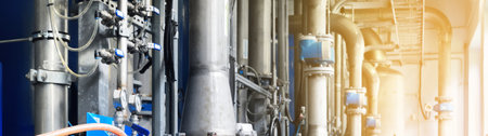 Large industrial water treatment and boiler room. Shiny steel metal pipes, blue pumps and valves....