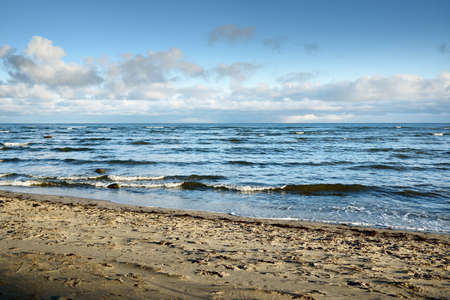 Panoramic view of the Baltic sea in winter. Clear blue sky with glowing cumulus clouds. Water surface texture, waves and water splashes close-up. Fickle weather, climate change, nature, seascapeの写真素材