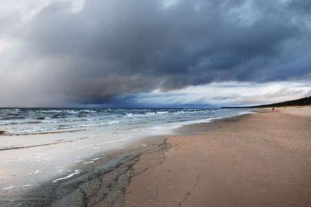Panoramic view of the Baltic sea at sunset. Dramatic sky with dark glowing cumulus clouds. Water surface texture close-up. Fickle weather, winter, climate change, nature, environmentの写真素材