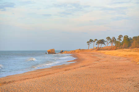Baltic sea shore (sand dunes) at sunset. Soft sunlight, clear sky, glowing clouds, waves. Idyllic seascape. Ziemelu Mols, Liepaja, Latvia, Europe. Travel destinations, ecotourism, natureの写真素材
