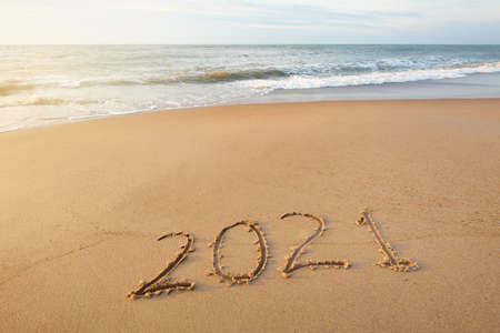 Numbers 2021 on the sandy beach at sunset, close-up. New year celebration concept. Idyllic panoramic...