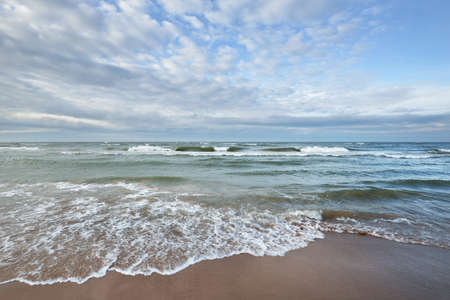 Panoramic view of the Baltic sea from a sandy shore (sand dunes). Dramatic sky with glowing clouds,...
