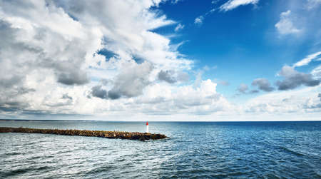 Dramatic blue sky above the Baltic sea, stormy clouds. Epic seascape. Lighthouse close-up. Panoramic aerial view, picturesque scenery. Travel, vacations, cruise, nature. Symbol of hope and peaceの写真素材