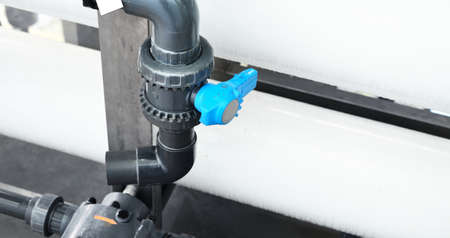 Large industrial water treatment and boiler room. Shiny steel metal pipes and blue pupms and valves.