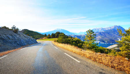 Asphalt curved mountain road in the french Alps near lake Lac de Serre-Poncon on a clear sunny...