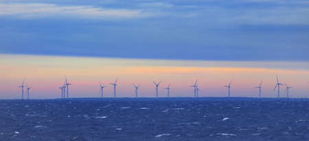 Seascape with offshore wind turbines on a sunset in the Baltic sea. Dramatic sky with glowing...