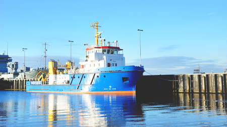 Moored tugboat and military ships on a pier in Kiel, Germany. Transportation, nautical vessel,...