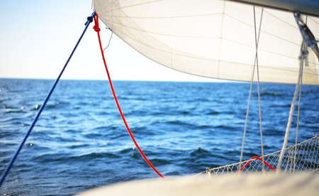 Close-up of the white staysail and its sheets from the deck of a yacht, sailing in an open sea on a...