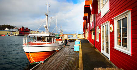 Small boat moored to a pier in a village in fjords. Rogaland region, Norway. Traditional...