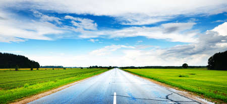 Wet asphalt countryside road (highway) on a sunny day. Dramatic sky. Electricity line close-up....