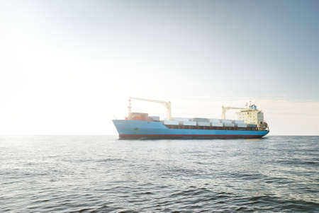 Large blue cargo container ship with a crane sailing in an open sea. USA. Freight transportation,...