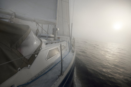 White yacht sailing in the Baltic sea. Thick fog. Sunrise. Sweden. Close-up view from the deck to...