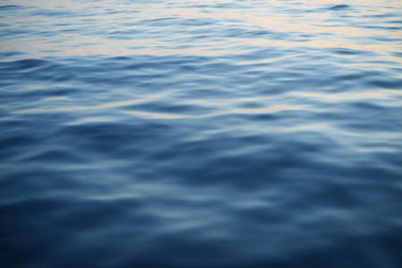 Calm water surface texture. Blue, azure, turquoise colors. Golden sunlight. Clear sky, reflections on water. Abstract natural pattern, background. Graphic resources, copy space. North sea, Norwayの写真素材
