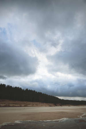 Dramatic blue sky with glowing cumulus clouds above the Baltic sea before sunset. View from a sandy shore. Autumn, early winter in Europe. Idyllic seascape. Fickle weather, climate change, ecologyの写真素材