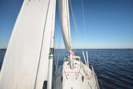White yacht sailing in the North sea after the storm. Norway. Top down view of the deck, mast, sail. Clear blue sky, soft sunlight. Transportation, cruise, recreation, regatta, sport, leisure activityの写真素材