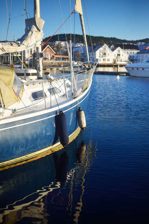 Blue sloop rigged yacht moored to a pier. Sunny winter day. Norway. Nautical vessel, transportation,...