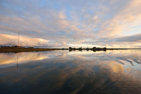 Bay with symmetry reflections in crystal clear water, natural mirror. Dramatic sky, ornamental...