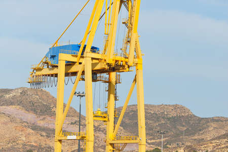 Terminal and cargo port, close-up of the yellow heavy crane. Mediterranean sea, Cartagena, Spain....
