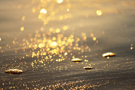 Sea shore at sunset, close-up. Pebbles, storm waves. Abstract background, details blurred in bokeh. Blue, yellow, orange, pink colors. Soft sunlight, golden hour. Peace, meditation, tranquility themesの写真素材