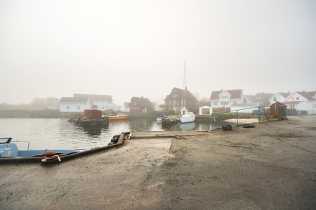Elegant and modern sailboats moored to a pier in a yacht marina. Thick white fog. Stavanger,...