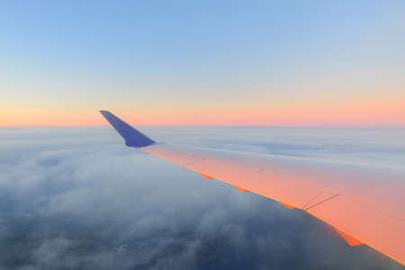 Golden sunset sky with fluffy ornamental cumulus clouds, panoramic view from an airplane, wing close-up. Dreamlike cloudscape. Travel, tourism, vacations, weekend, freedom, peace, hope conceptsの写真素材
