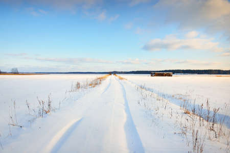 Panoramic view of the country ice road through snow-covered field with haystacks. Winter rural scene. Christmas, travel, logistics, dangerous driving, off-road, transportation, speed, freedomの写真素材