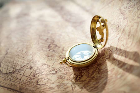 Retro styled golden compass (sundial) and old white nautical chart. Vintage still life. Sailing accessories. Travel, navigation, collecting, 3D modeling, souvenir, gift, graphic resources, copy spaceの写真素材